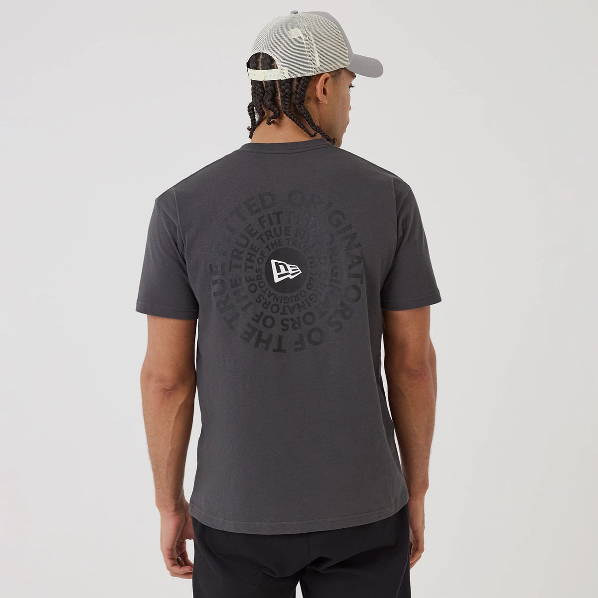 New Era Circle Grey T-Shirt, rear view showing a circular design with dark text around a white raised New Era logo, centred on the upper back of the grey shirt worn by a person in a light grey cap.