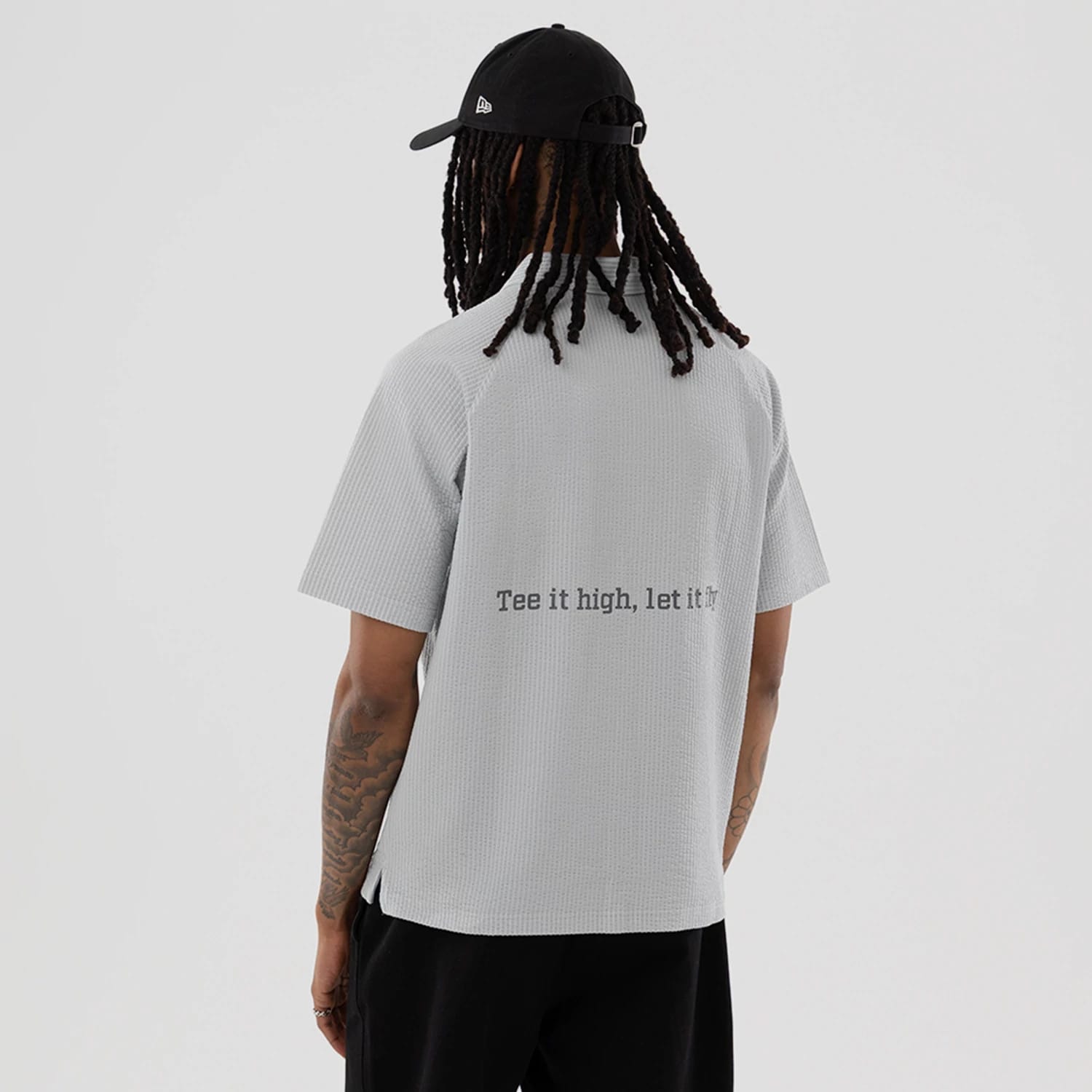 The model is wearing this New Era Seersucker Polo T-Shirt in grey. 2