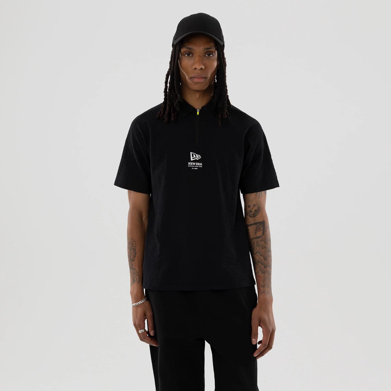 The model is wearing this New Era Seersucker Polo T-Shirt in black. 1