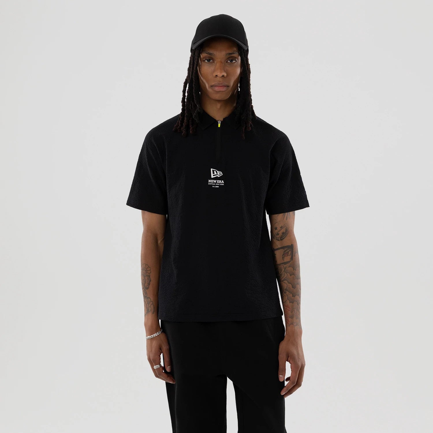 The model is wearing this New Era Seersucker Polo T-Shirt in black. 1
