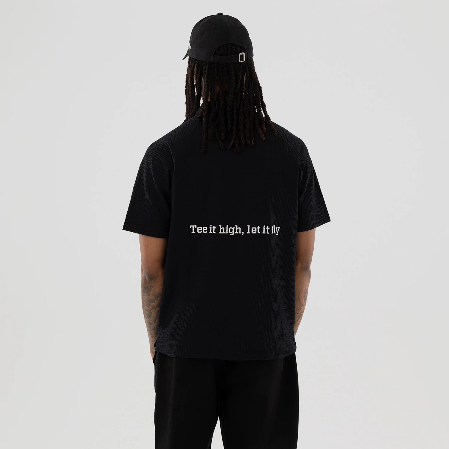 The model is wearing this New Era Seersucker Polo T-Shirt in black. 2