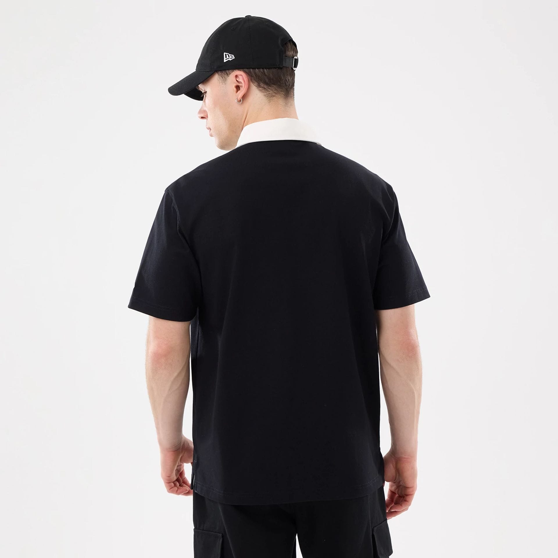 The model is wearing this New Era Short Sleeve Rugby Shirt in black. 2