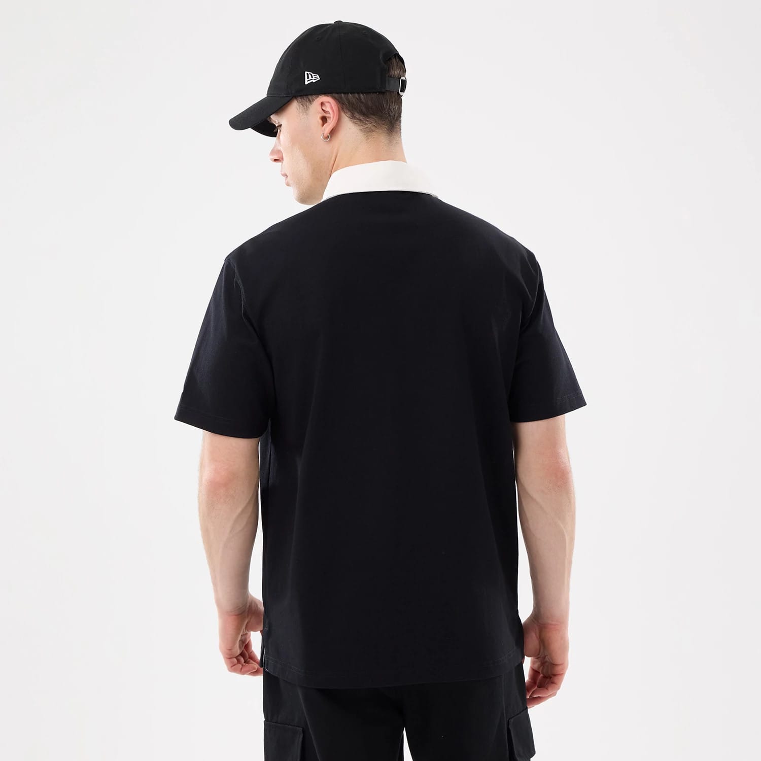 The model is wearing this New Era Short Sleeve Rugby Shirt in black. 2