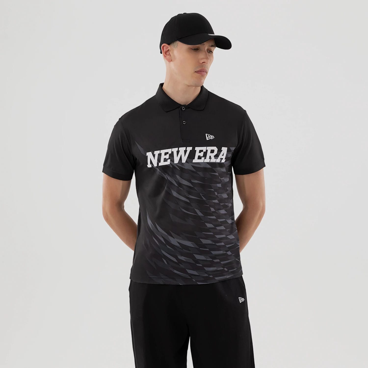 The model is wearing this New Era Grid Polo T-Shirt in black. 1