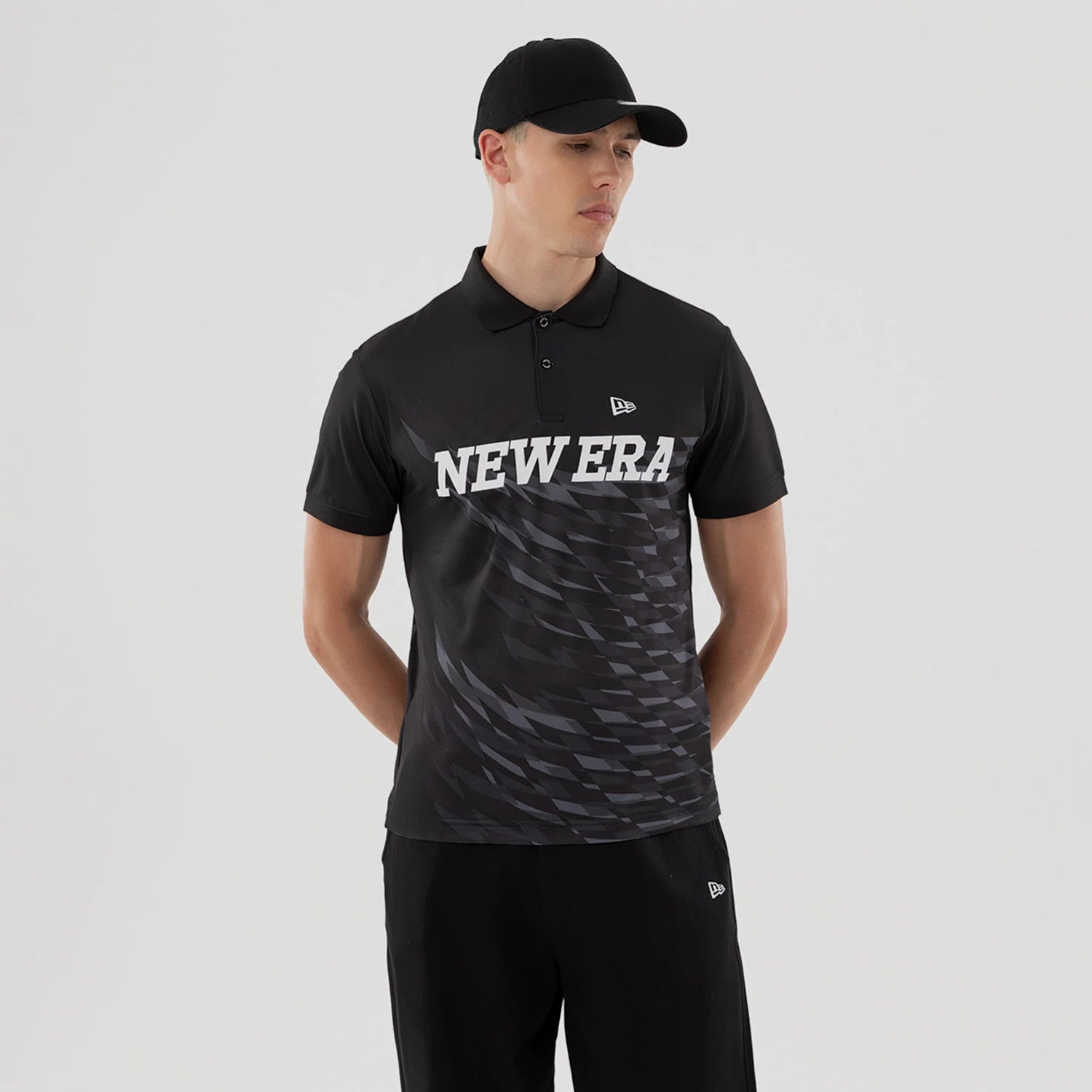 The model is wearing this New Era Grid Polo T-Shirt in black. 1