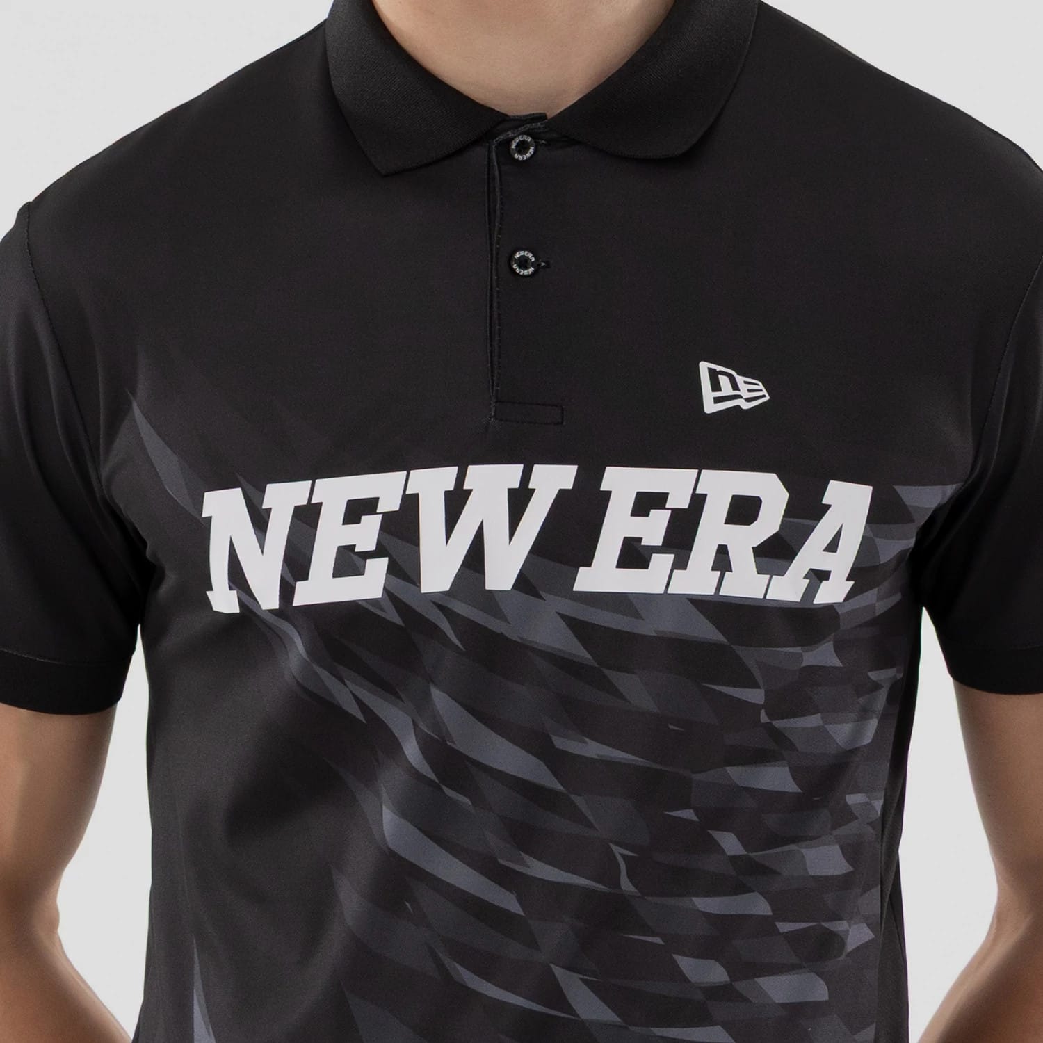 The model is wearing this New Era Grid Polo T-Shirt in black. 4