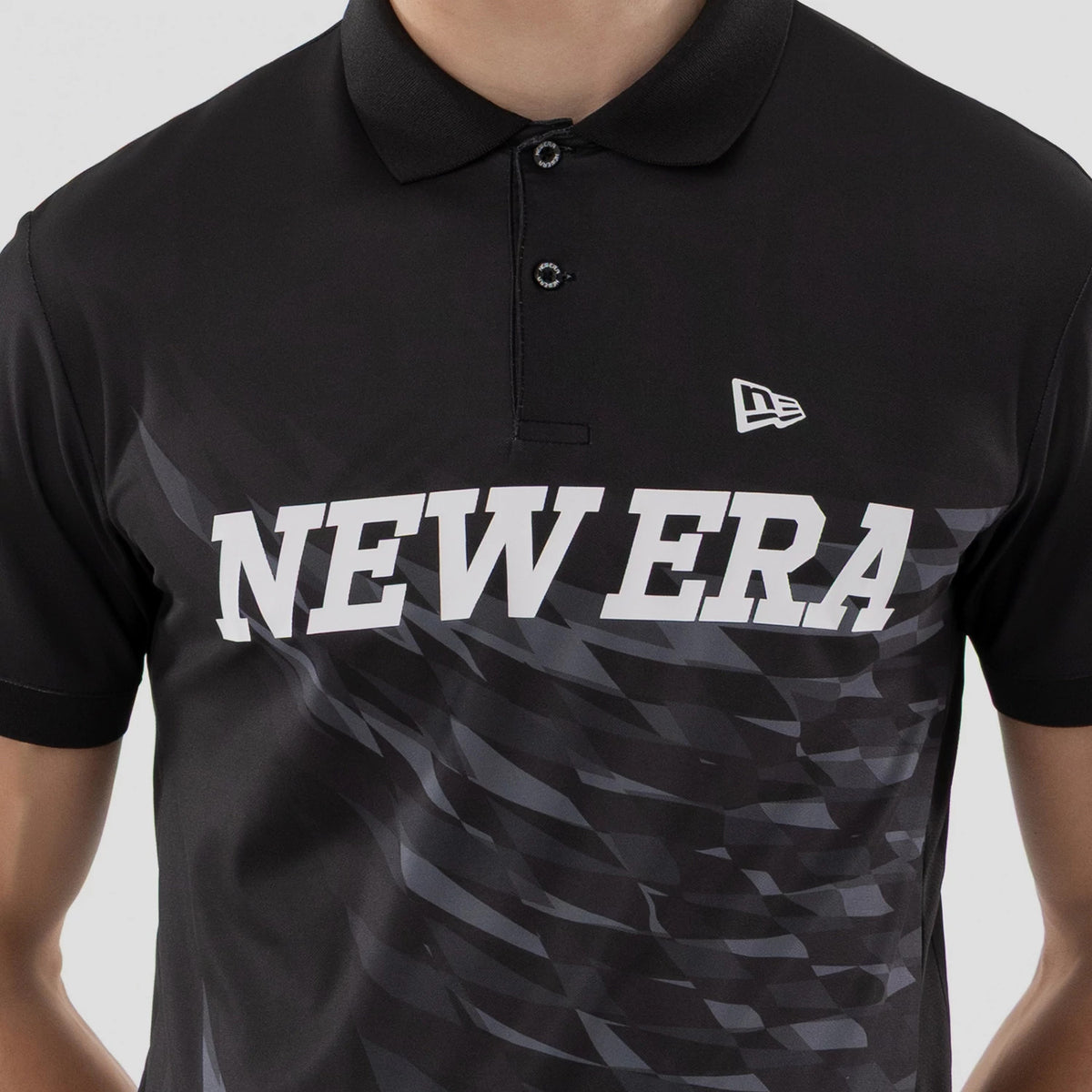 The model is wearing this New Era Grid Polo T-Shirt in black. 4