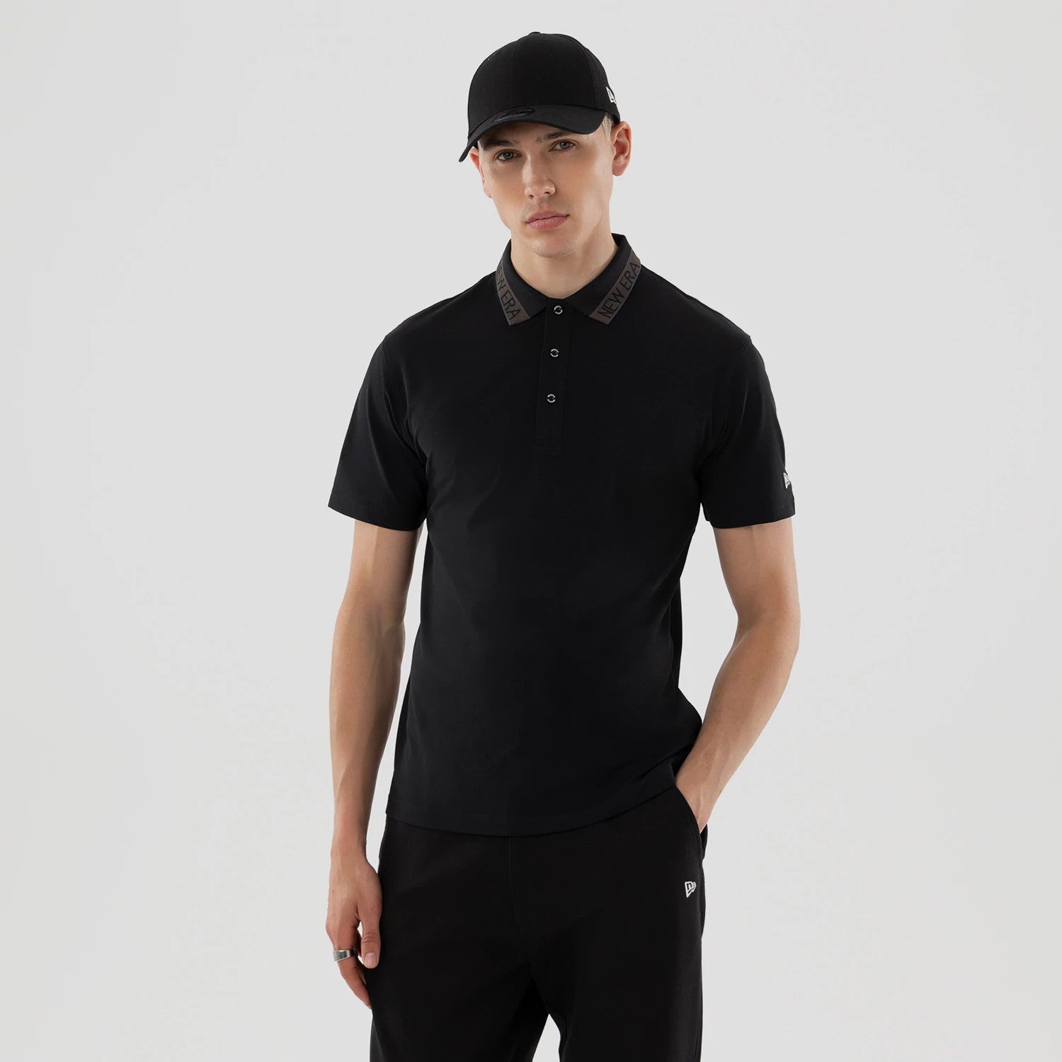 The model is wearing this New Era Kanoko Polo T-Shirt in black. 1