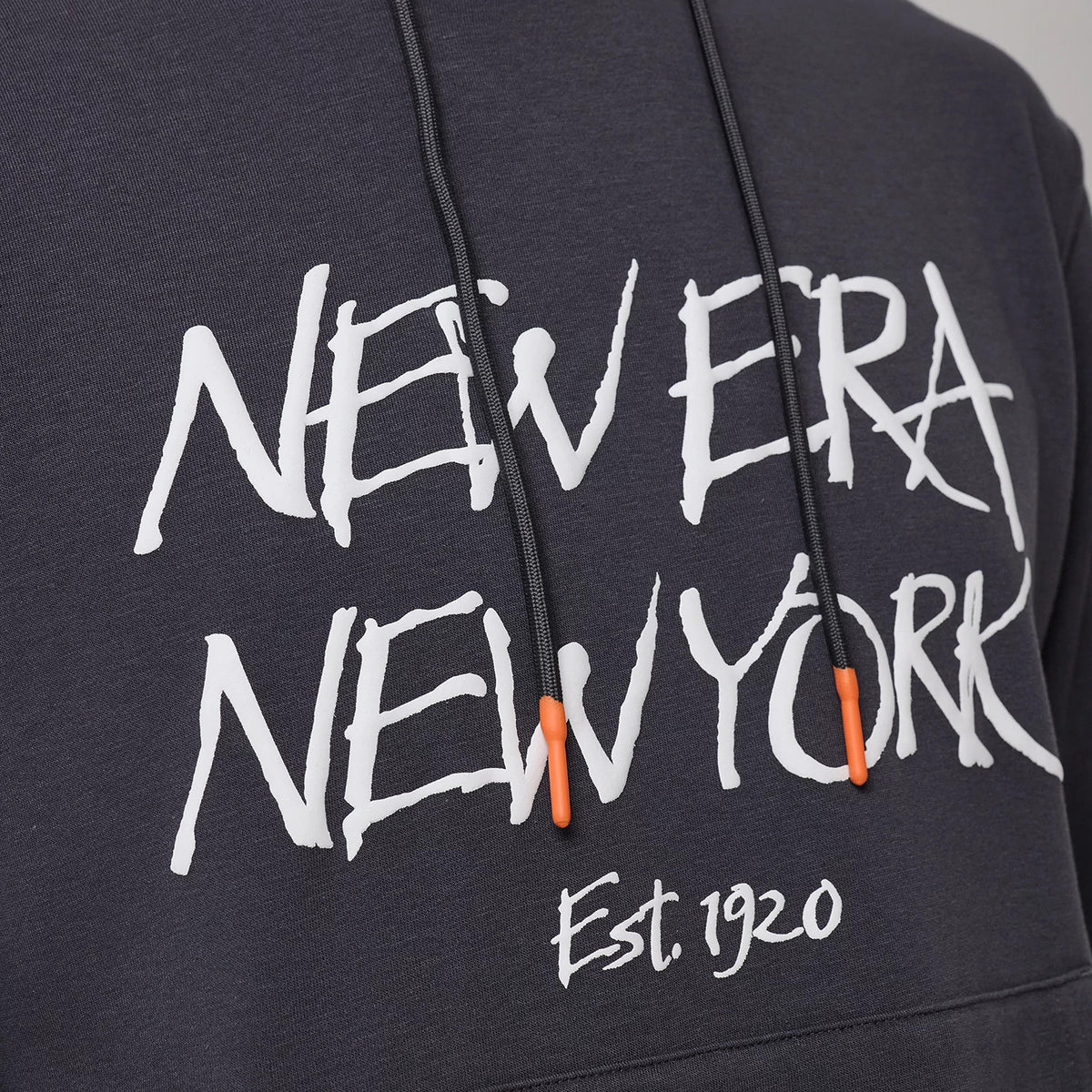 New Era New York Dark Grey Oversized Pullover Hoodie, front view showing the large white printed text "New Era New York" across the chest, black drawstrings with orange tips, and the script "Est. 1920" below.