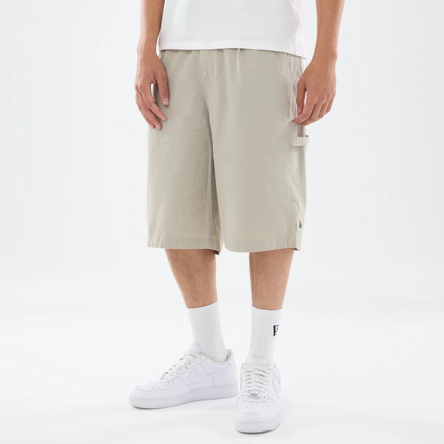 The model is wearing this New Era Canvas Bermuda Shorts in beige. 1