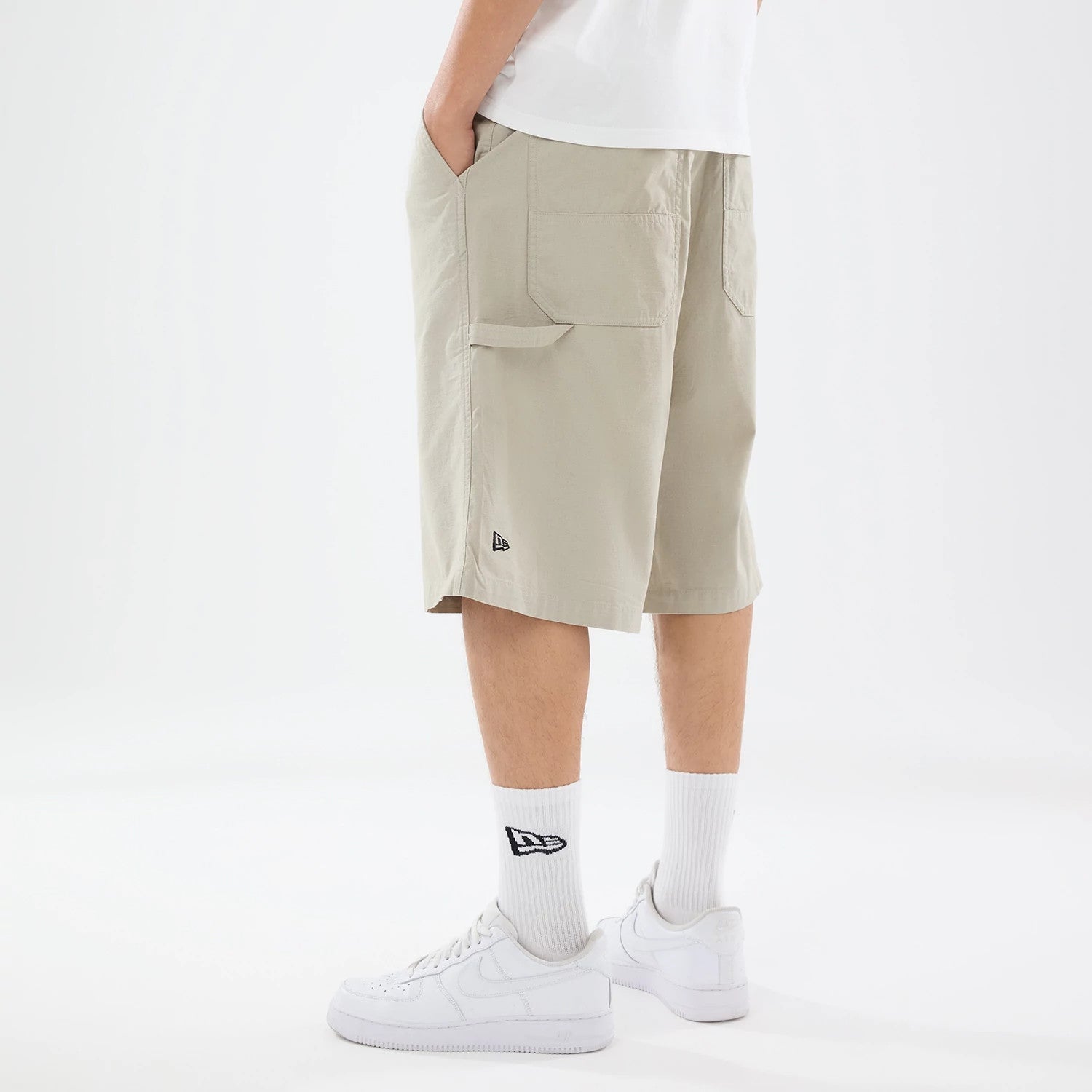The model is wearing this New Era Canvas Bermuda Shorts in beige. 2