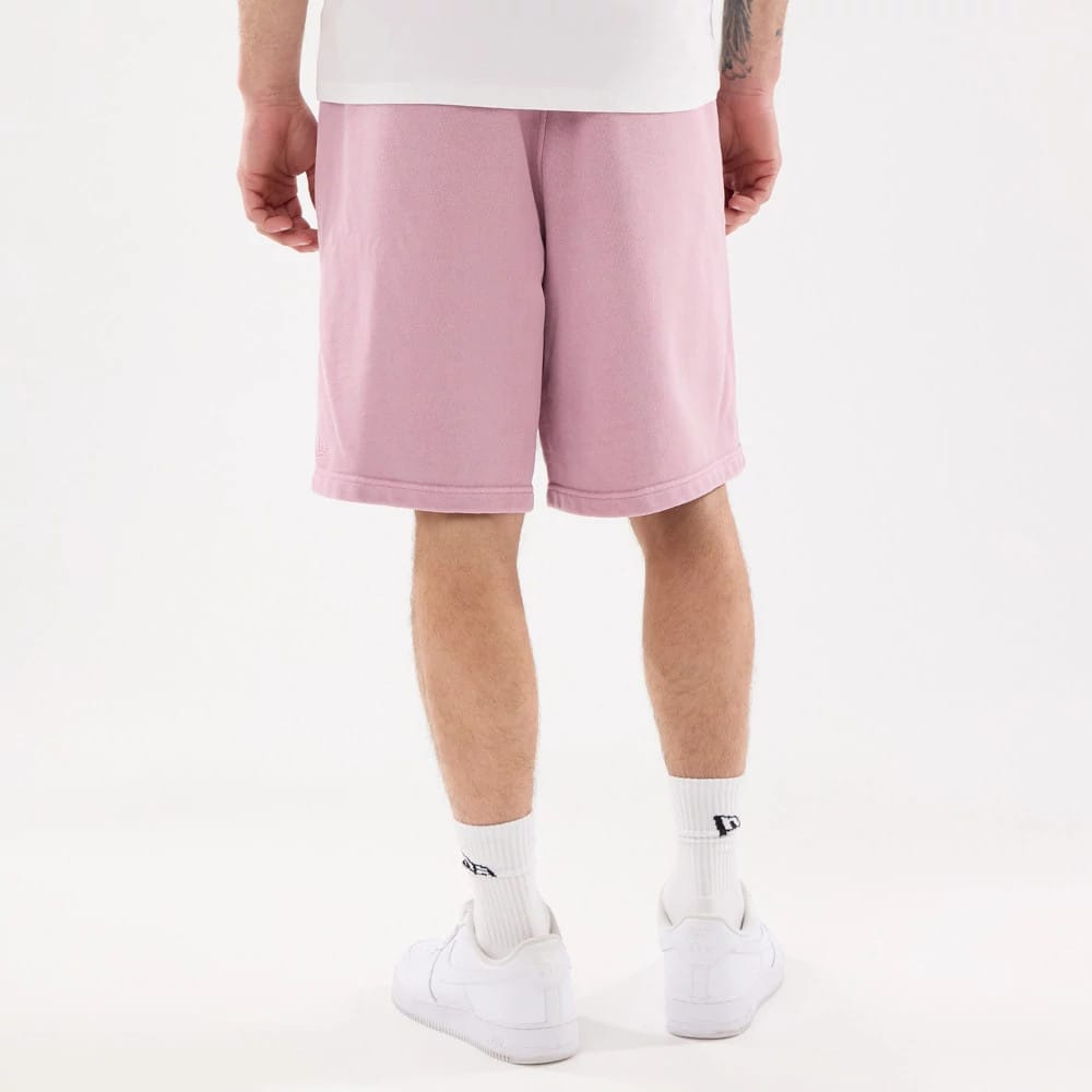 New Era Originators Pink Oversized Shorts, rear view showing the light pink colour on mid-length shorts, ending above the knees, a debossed New Era logo near the lower left hem on the back.