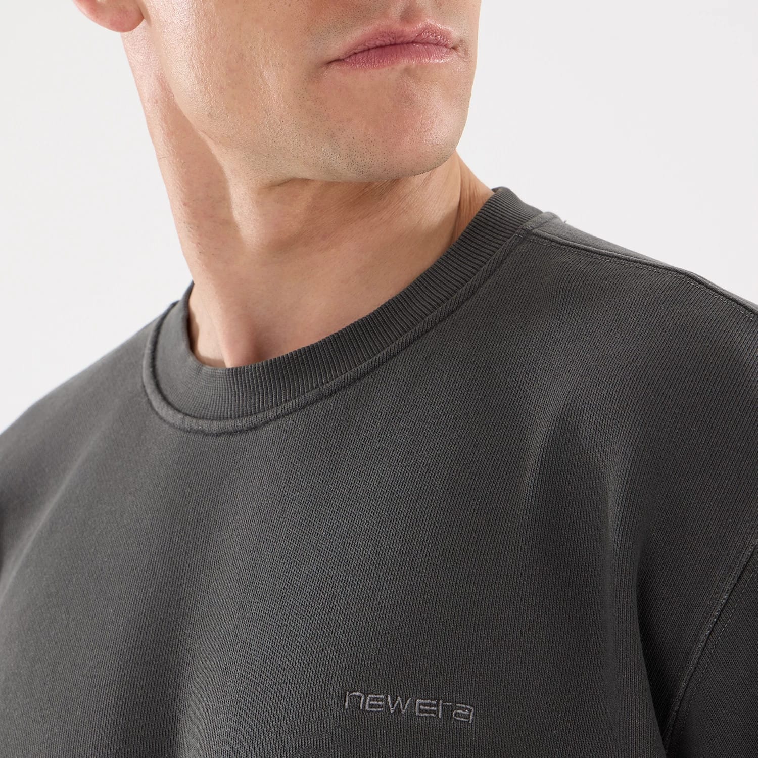 New Era Originators Black Crew Neck Sweater, on-model view showing the ribbed crew neck and subtle embroidered new era logo on the chest, highlighting the sweater's sleek design and comfortable fit.