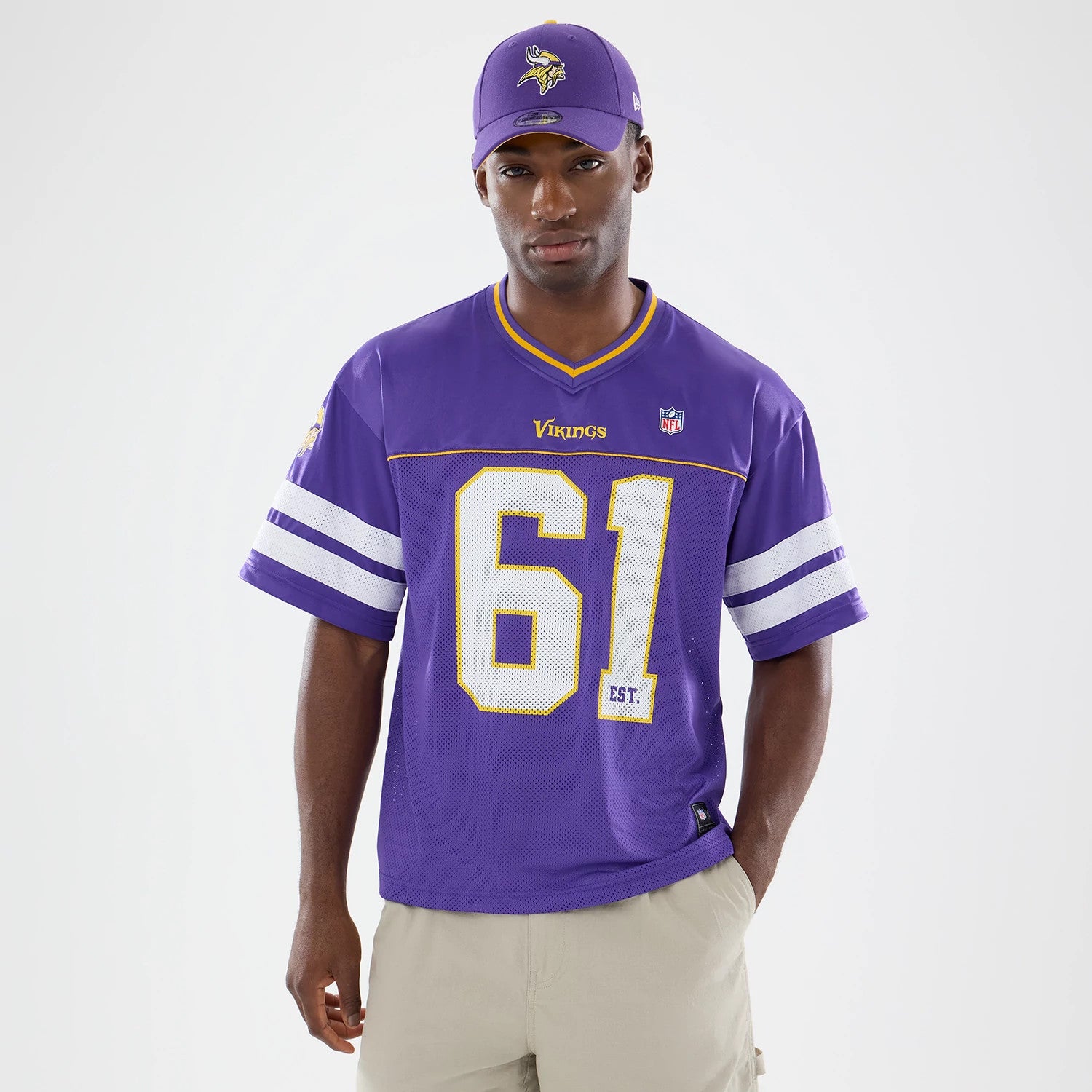 Minnesota Vikings NFL Purple Mesh Jersey, front view on a model styling the vibrant purple jersey with bold golden Vikings text, number 61 in white and yellow outline, and white sleeve stripes, complemented by a matching purple cap.