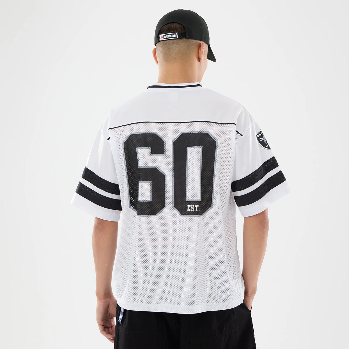 Las Vegas Raiders NFL White Mesh Jersey, back view on a model wearing the jersey, featuring the number 60 and 'EST.' lettering in black on the white mesh fabric, with sleeve stripes and Raiders shield logo on the left sleeve.