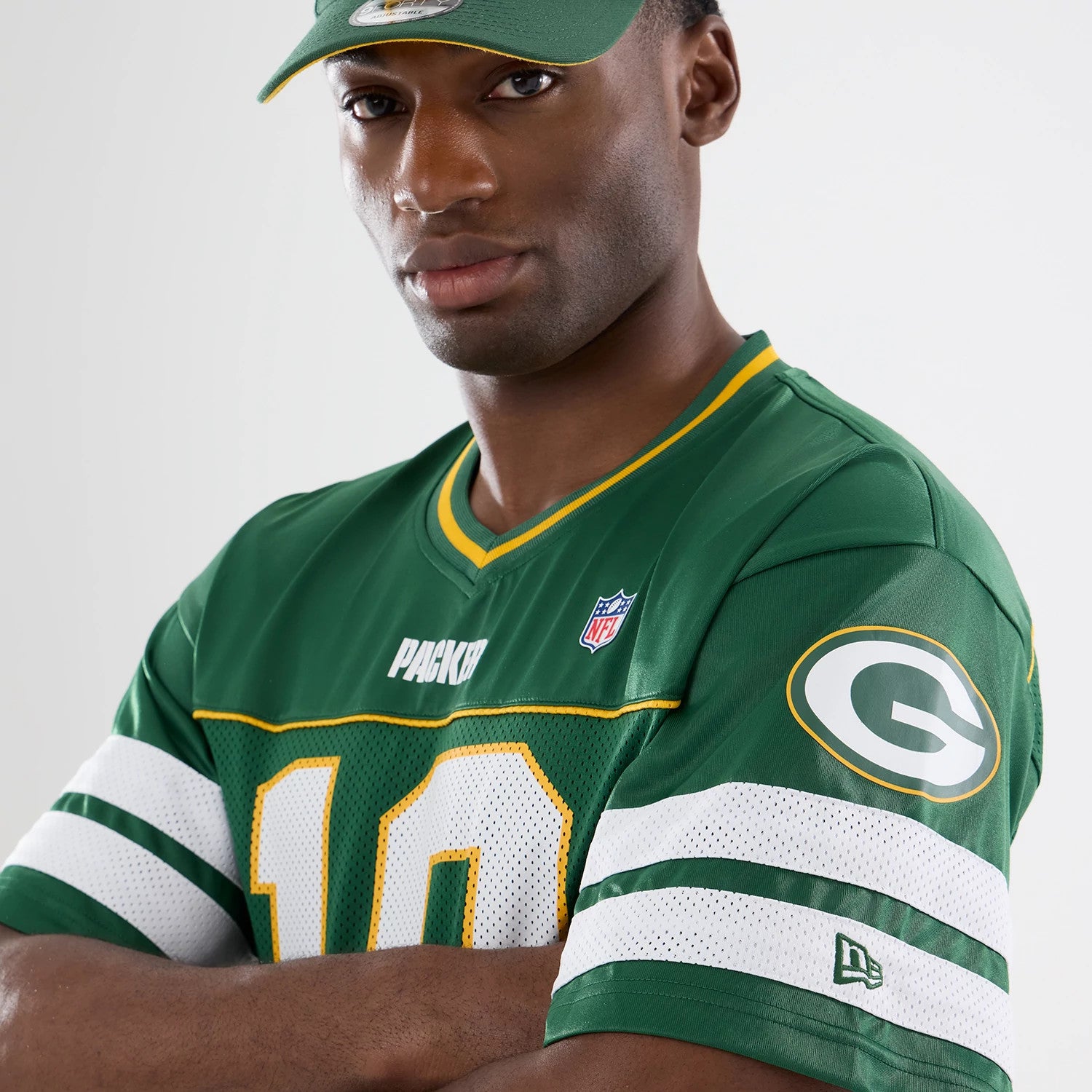 Green Bay Packers NFL Green Mesh Jersey, front view on a model with arms crossed, showcasing the bold number 10 in white and yellow on the front, Packers wordmark on the chest, and the New Era flag logo on the left sleeve.
