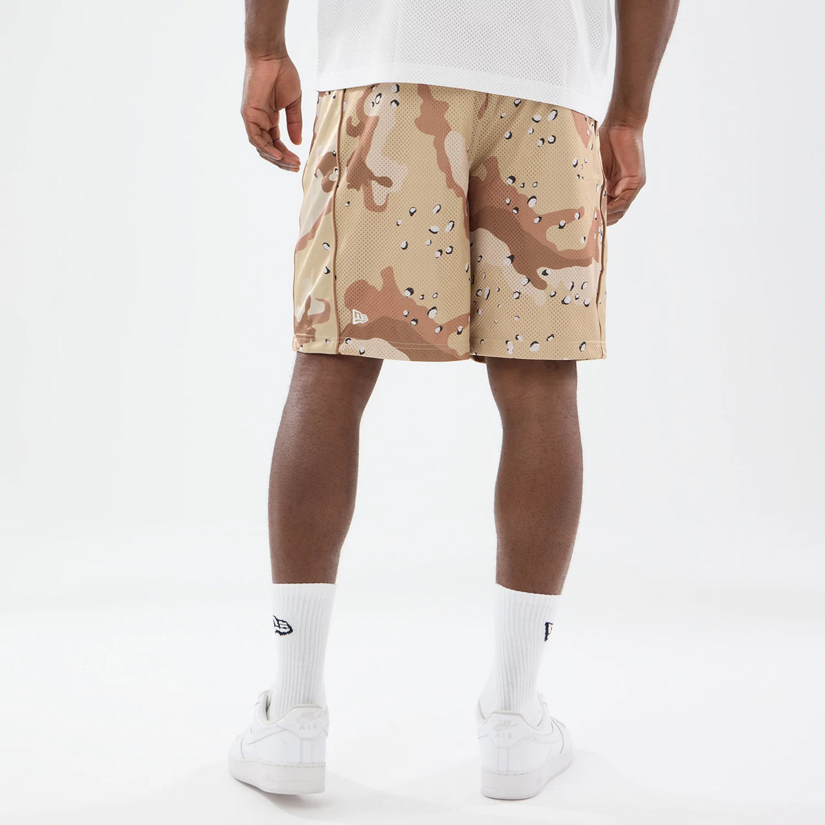 New Era Bermuda Woodland Camo Oversized Shorts, rear view showing the beige and brown camo pattern across the entire fabric, debossed New Era logo on the left leg near the hem, garment draping loosely to the knees.