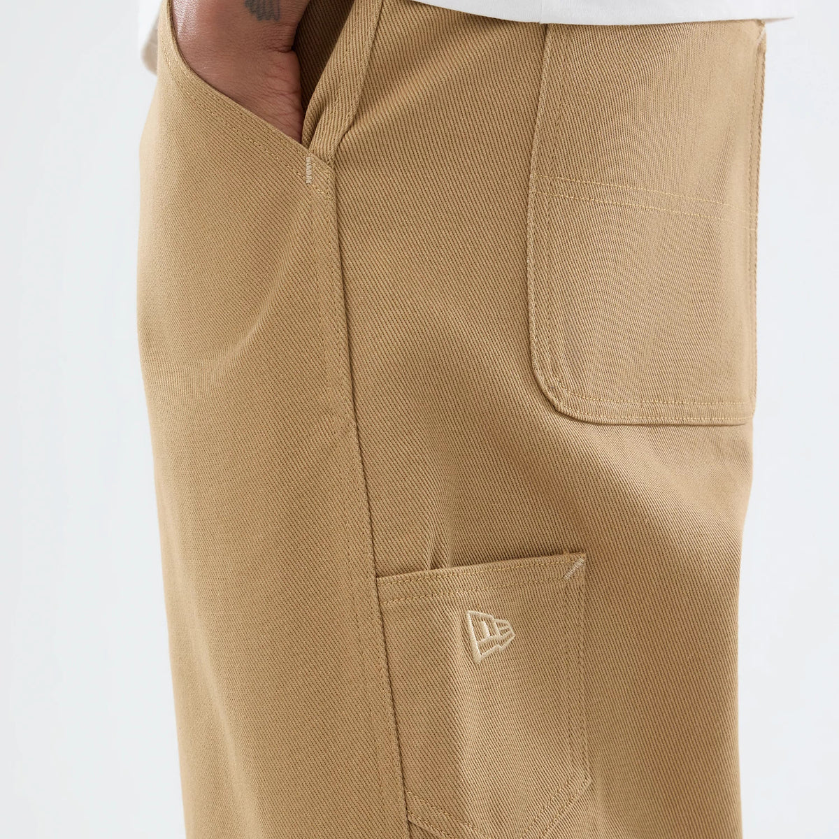 The model is wearing these New Era Work Pants in beige. 4