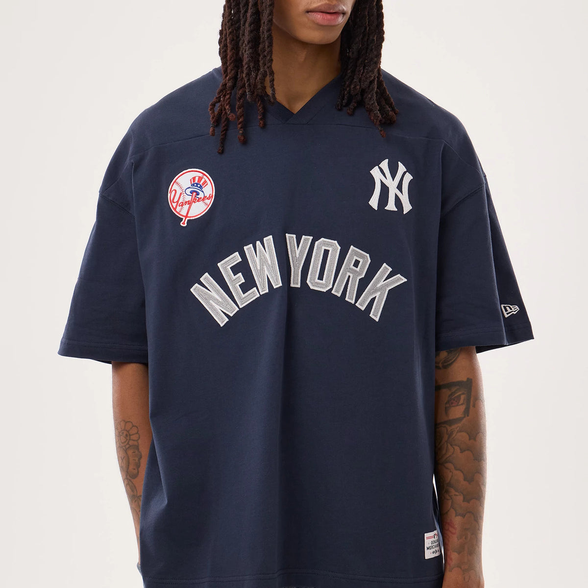 New York Yankees MLB Fan Family Navy Jersey, front view on a model showing the white embroidered NY logo on the right chest, Yankees circular patch on the left chest, and oversized New York lettering across the front.