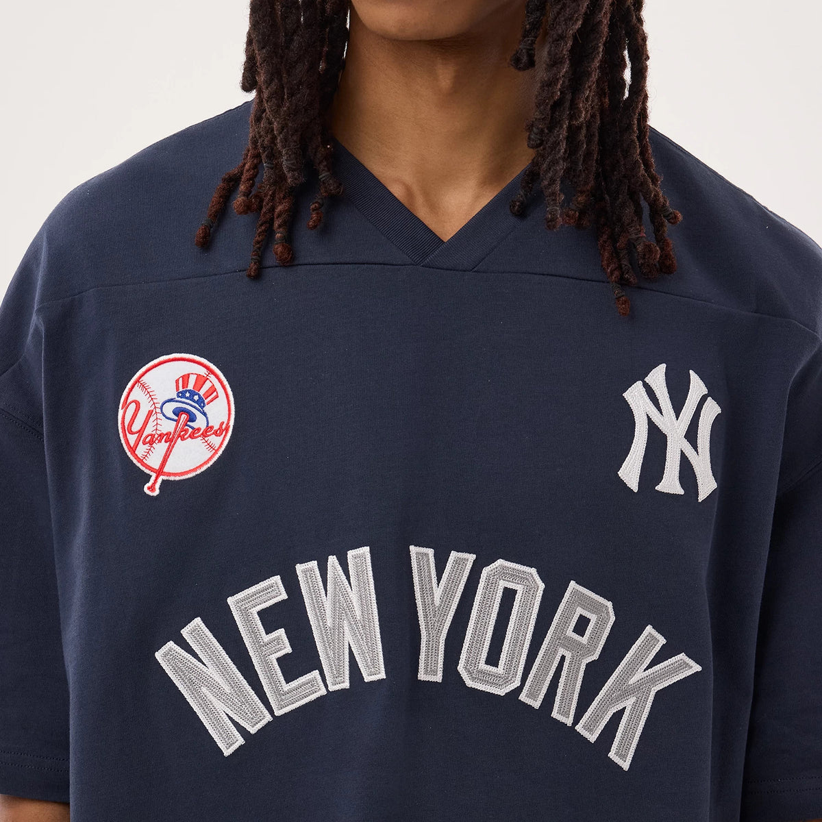 New York Yankees MLB Fan Family Navy Jersey, front view on a model showing embroidered Yankees logo on the left chest, team emblem on the right chest, and bold "NEW YORK" lettering across the front.