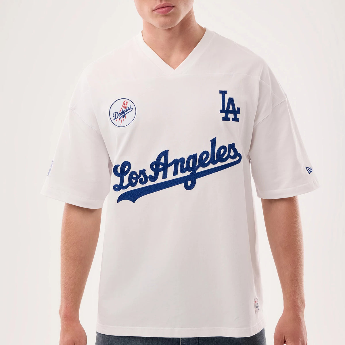 Los Angeles Dodgers MLB Fan Family White Jersey, front view on a model showing the blue embroidered LA logo on the left chest, Los Angeles script across the chest, and a Dodgers patch on the right shoulder.