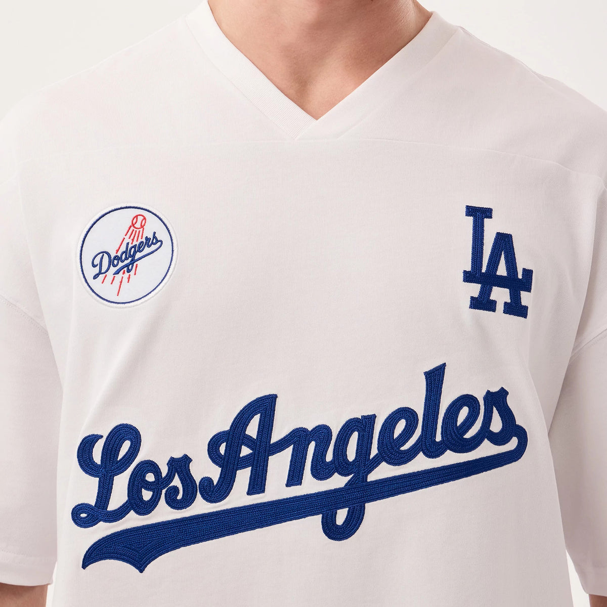 Los Angeles Dodgers MLB Fan Family White Jersey, front view on a model showing the blue embroidered LA logo on the left chest, the Dodgers logo on the right shoulder, and Los Angeles script across the front.