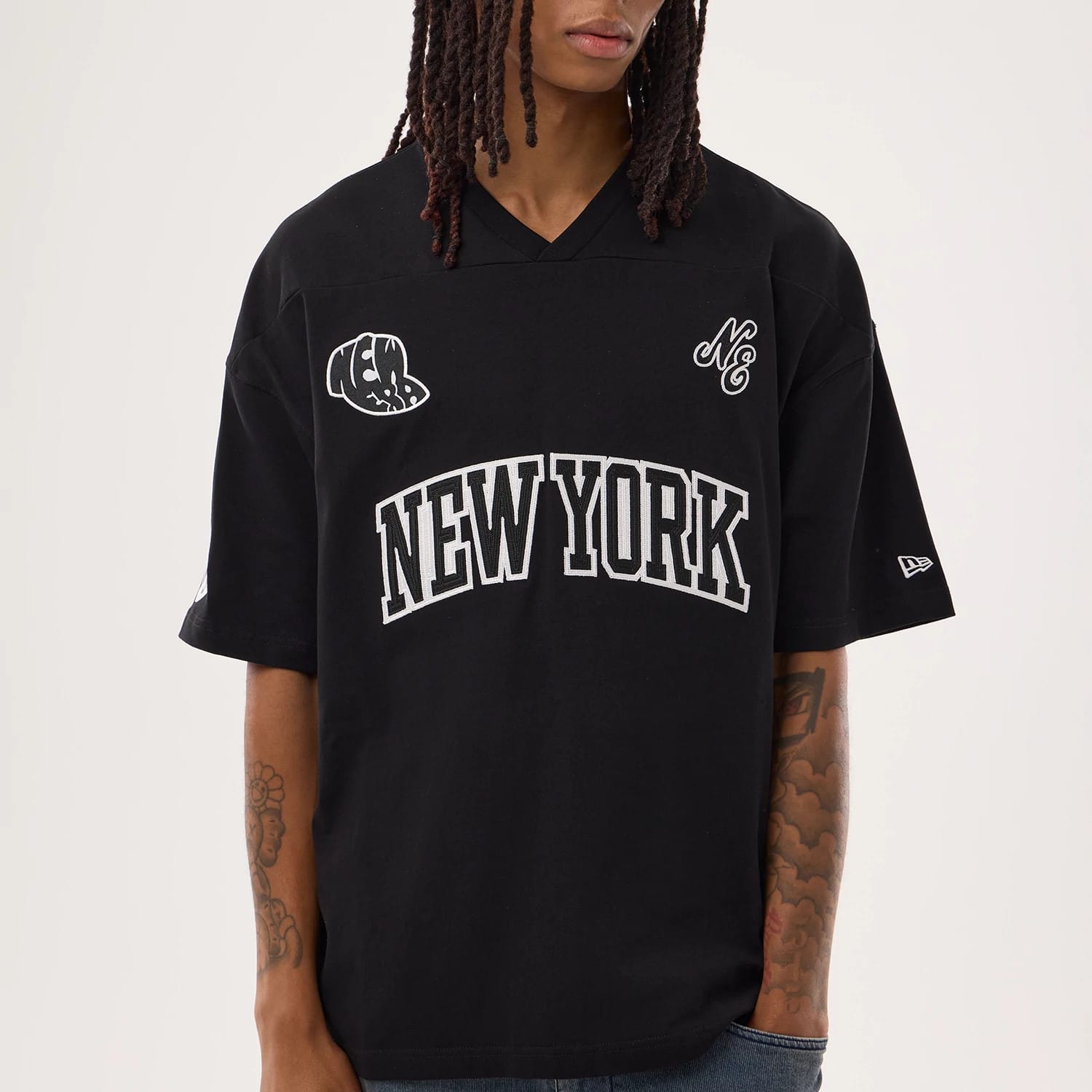 New Era Fan Family Black Jersey, front view on a model showing New York text in white across the chest, embroidered team logos on the sleeves and chest, with casual styling and a v-neckline.