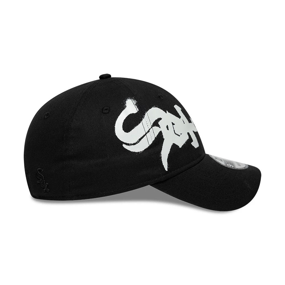 Chicago White Sox MLB Spray Paint Black New Era 9FORTY Adjustable Cap, side view with a white spray-paint style logo on the front panel and curved black visor, featuring a 9FORTY size sticker and an embroidered White Sox logo on the left side.