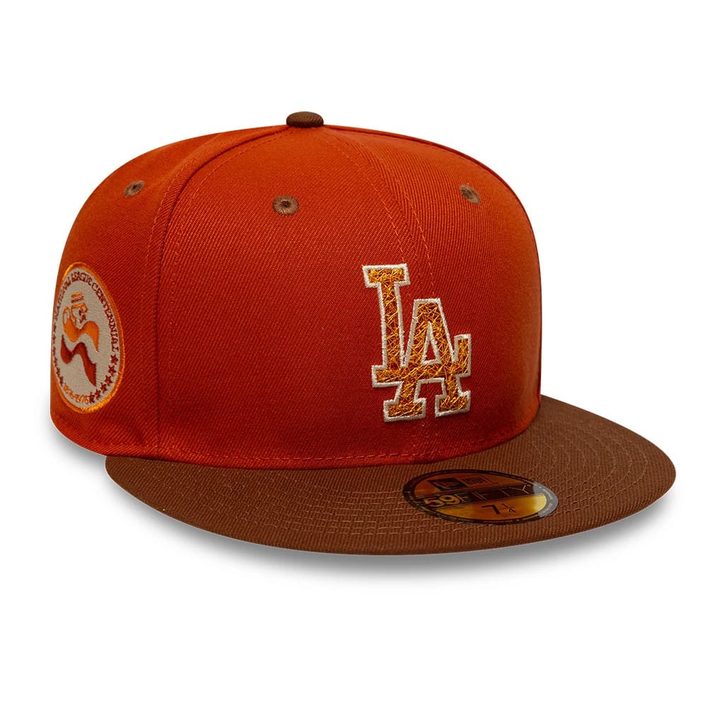 Los Angeles Dodgers MLB Pack Dark Orange New Era 59FIFTY Fitted Cap, three-quarter view showing the raised golden LA logo on the front panel, a brown visor with gold 59FIFTY size sticker, and embroidered patch on the left side.