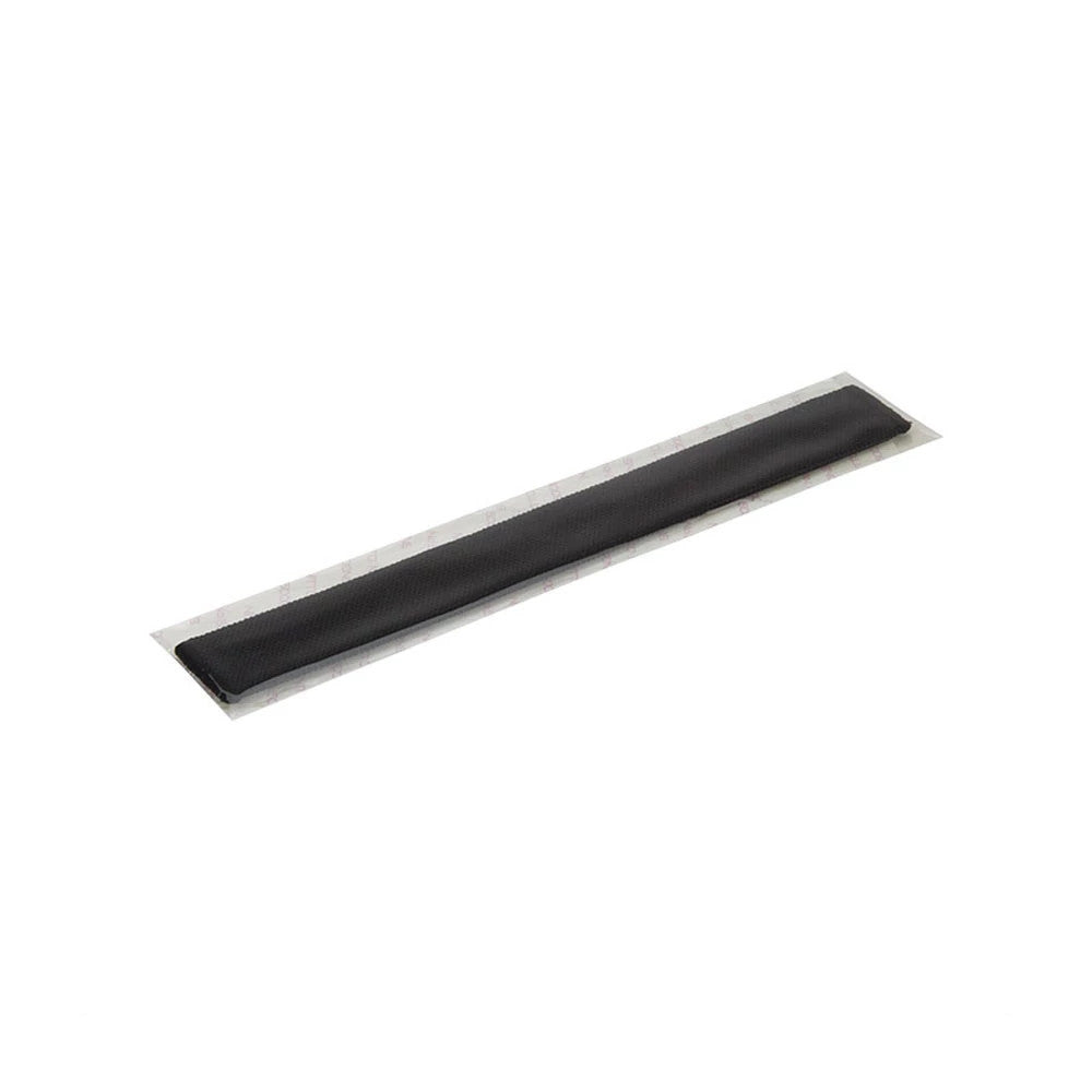 New Era Black Cap Liner, close-up showing the sleek rectangular shape of the black liner, packaged in clear plastic wrapping with adhesive backing visible, designed for placement inside caps for added comfort.