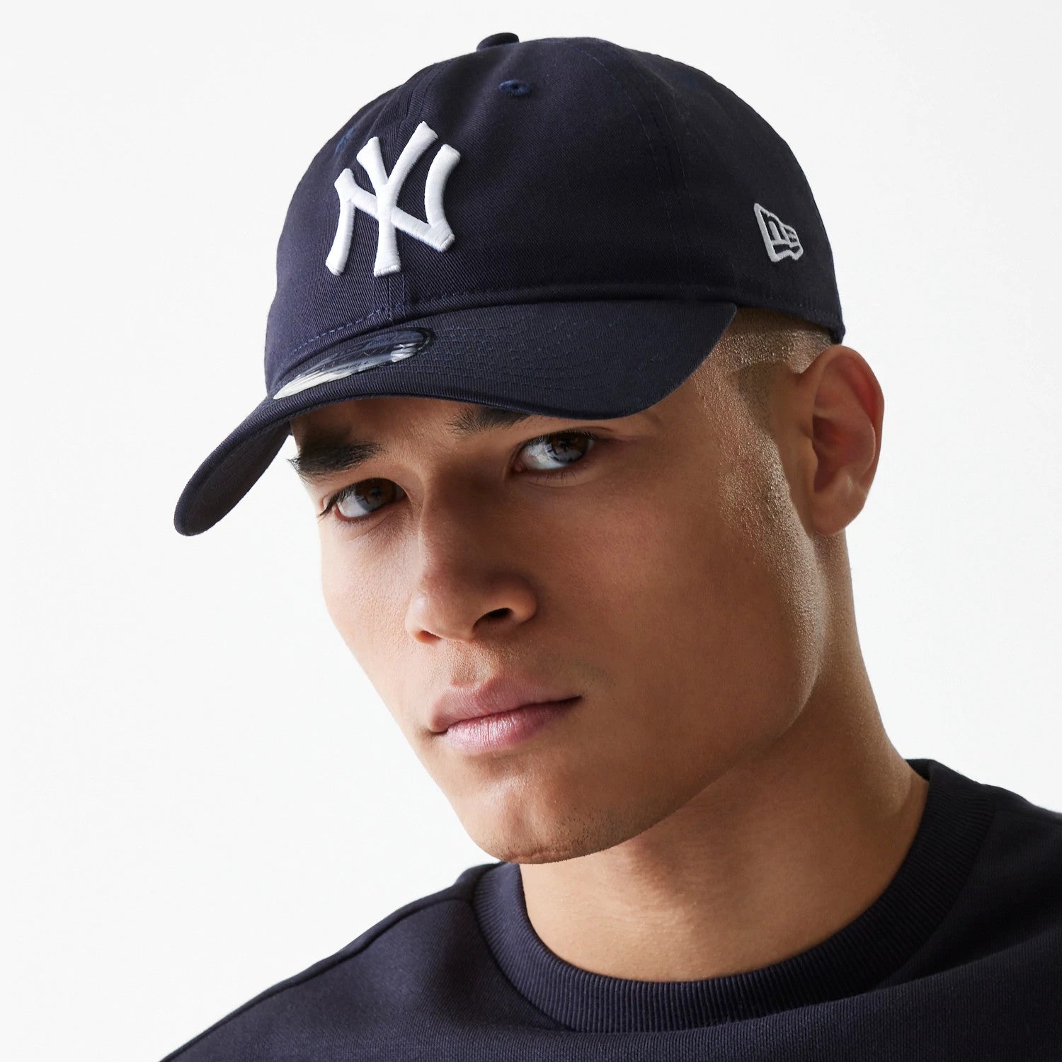 New York Yankees League Essential Navy New Era 9TWENTY Adjustable Cap, on-model front view with a white embroidered NY logo on the front panel, curved visor with a 9TWENTY size sticker, and a New Era flag logo on the left side.