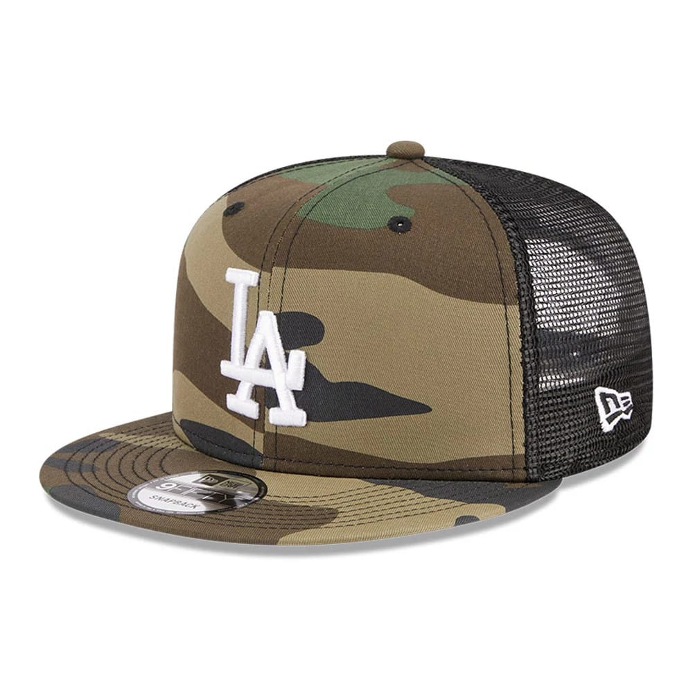 LA Dodgers MLB Evergreen Camo New Era 9FIFTY Trucker Adjustable Cap, front view showing a raised white embroidered LA logo on the camouflage front panel, a black mesh back, and a 9FIFTY size sticker on the flat visor.