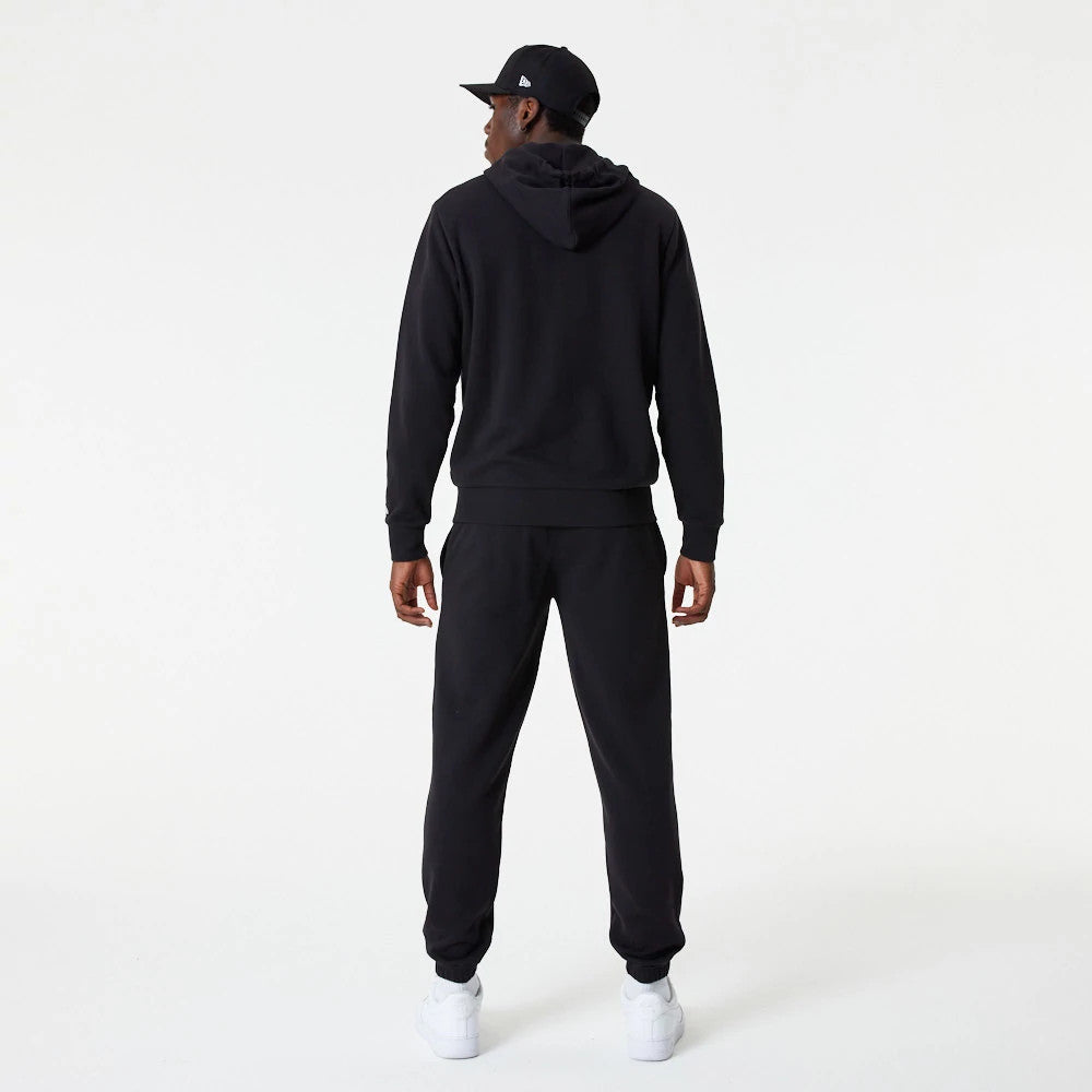 LA Dodgers MLB Essential Black Full Zip Hoodie, rear view showing the black hoodie with a full-length zip, a loose fitted hood, and plain cuffs, paired with matching black trousers and white trainers.