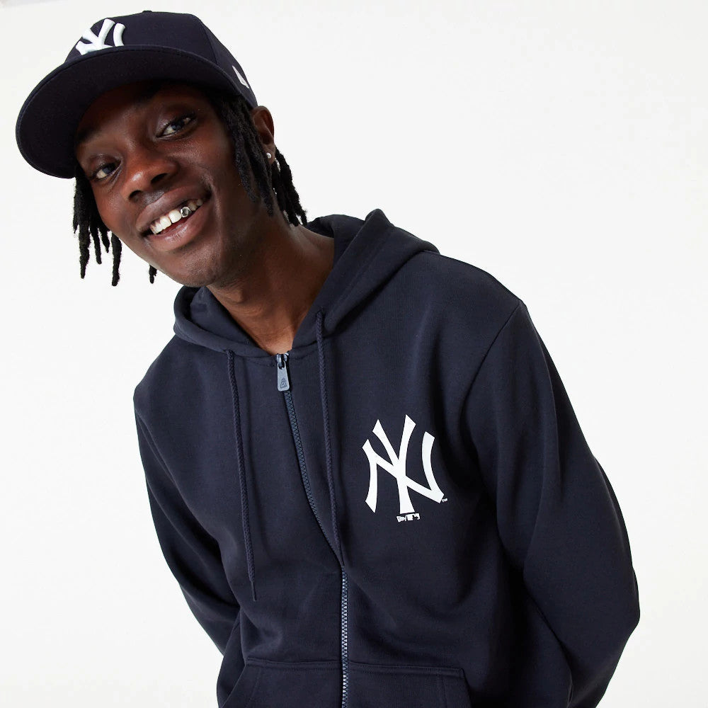 New York Yankees MLB Essential Navy Full Zip Hoodie, on-model view showing the navy hoodie with a full zip running down the front, white NY logo printed on the left chest, and a man wearing a matching navy cap with the NY logo.