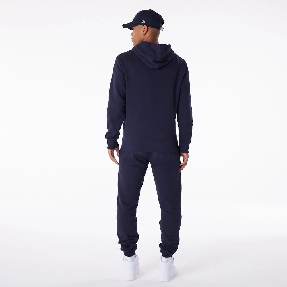 New York Yankees MLB Essential Navy Full Zip Hoodie, on-model rear view showing a plain navy back with a hood down, paired with matching navy trousers, and a raised New Era logo on the side of a navy cap worn by the model.