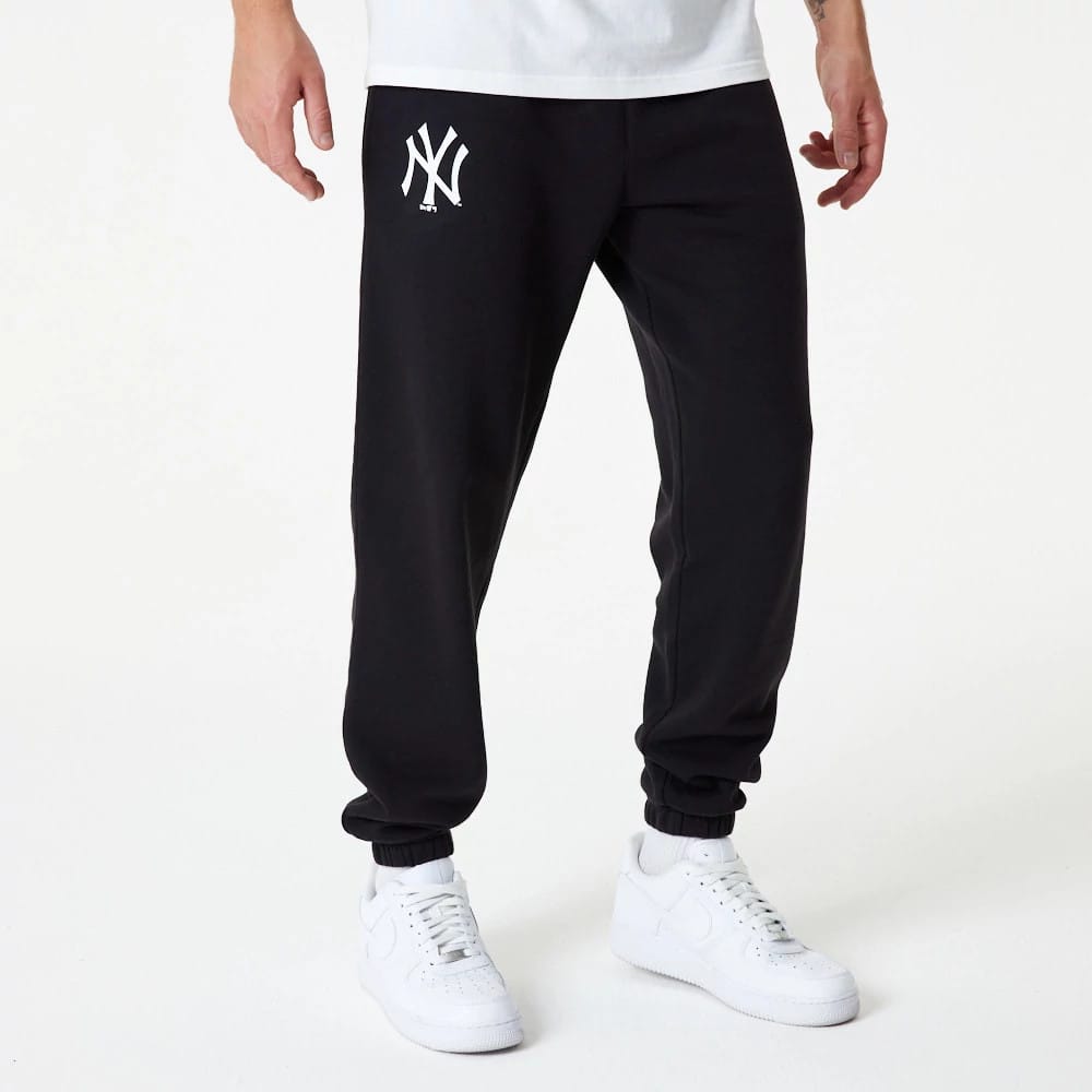 New York Yankees MLB Essential Black Joggers, front view on a model with white trainers showing the white embroidered NY logo on the right thigh and elasticated ankle cuffs for a snug fit.