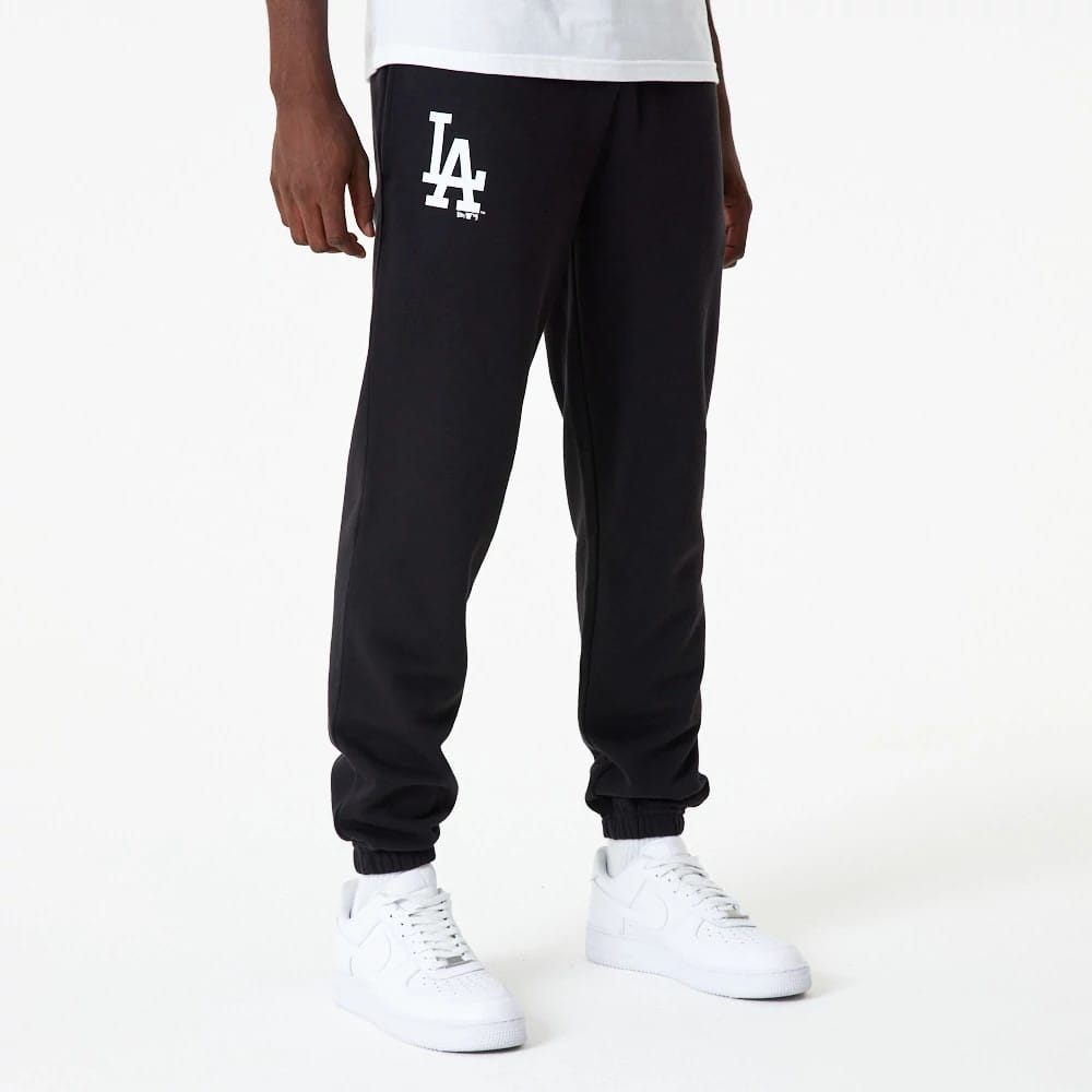 New Era LA Dodgers MLB Essential Black Joggers, front view on a model with an LA logo in white on the upper left leg and black elasticated cuffs, paired with a white T-shirt and white trainers.