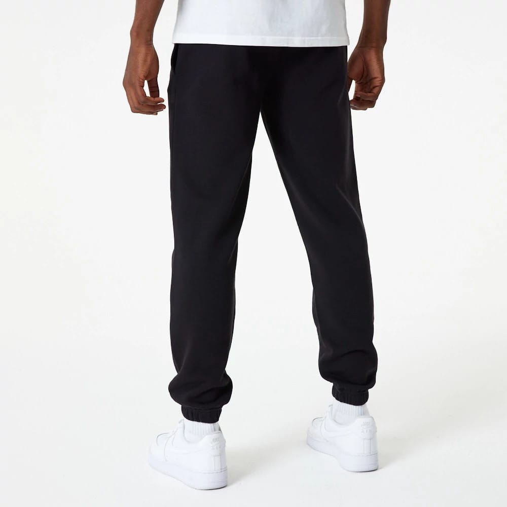 New Era LA Dodgers MLB Essential Black Joggers, rear view on a model wearing a white T-shirt and white sneakers, featuring an elasticated waistband and ankle cuffs that provide a snug fit, with a straight leg design.