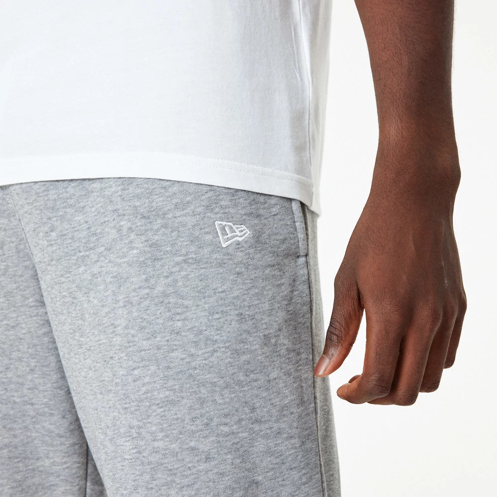 LA Lakers NBA Essential Grey Joggers, close-up on a model with a white New Era flag logo embroidered near the left pocket, showcasing the soft grey fabric alongside a white t-shirt.