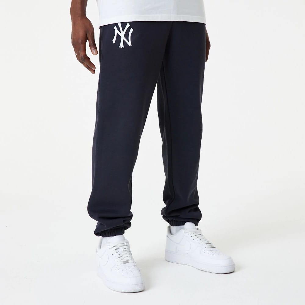 New York Yankees MLB Essential Navy Joggers, front view on a model wearing white trainers, featuring the white embroidered Yankees logo on the left upper thigh and elasticated cuffs.