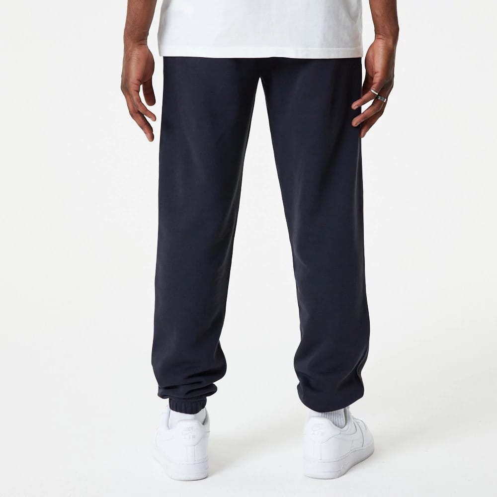 New Era New York Yankees MLB Essential Navy Joggers, rear view on a model showing the elasticated cuffs at the ankles and a relaxed fit, paired with a white t-shirt and white trainers.
