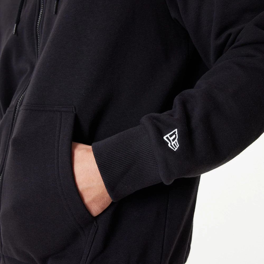 Chicago Bulls NBA Essential Black Full Zip Hoodie, side view showing a black sleeve with a ribbed cuff and a white embroidered logo on the wrist, alongside a partially zipped front and a visible front pocket with a hand inside.