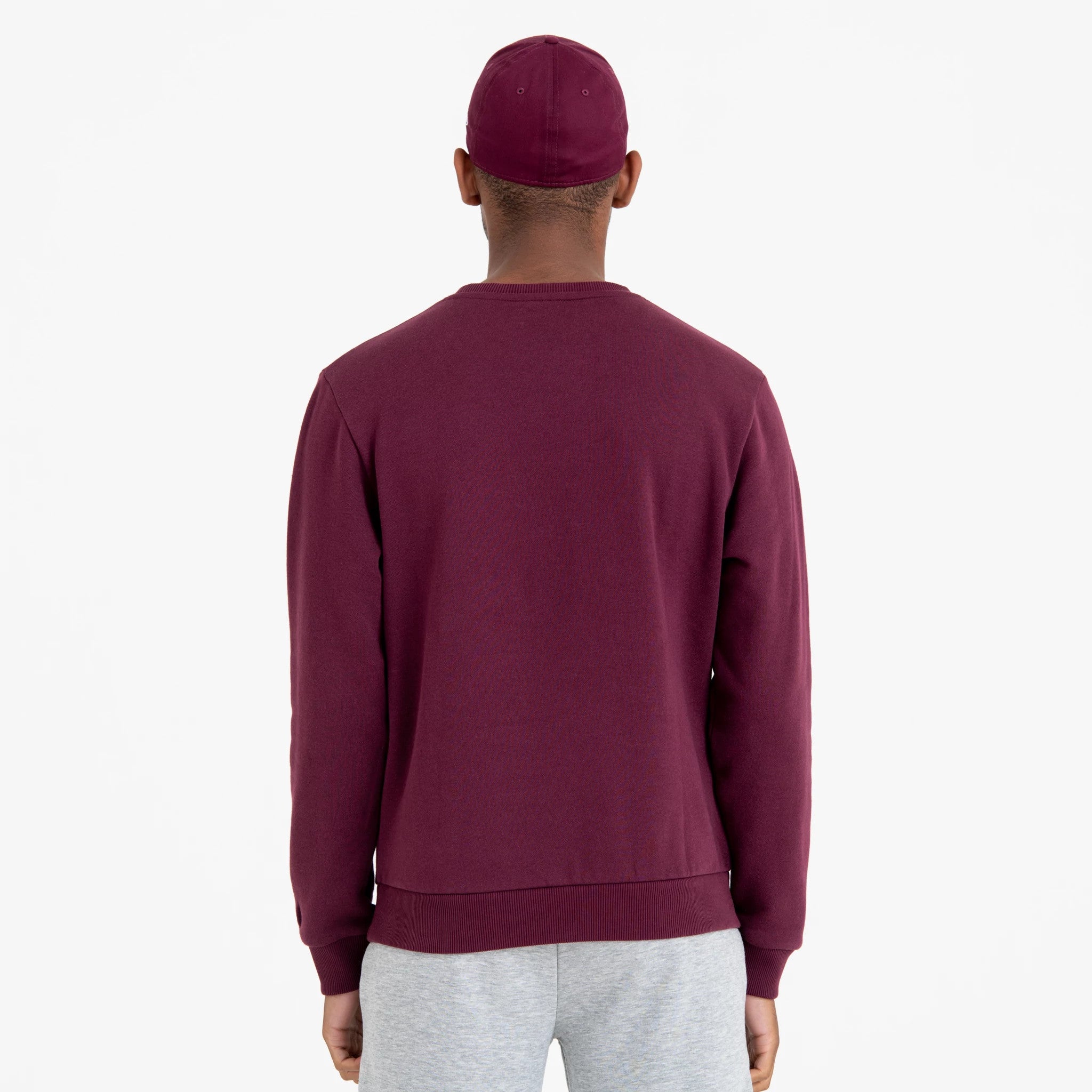 New York Yankees MLB Regular Dark Purple Crew Neck Sweatshirt, back view on a model wearing a matching dark purple cap, highlighting the sweatshirt's ribbed collar and cuffs, paired with light grey joggers.