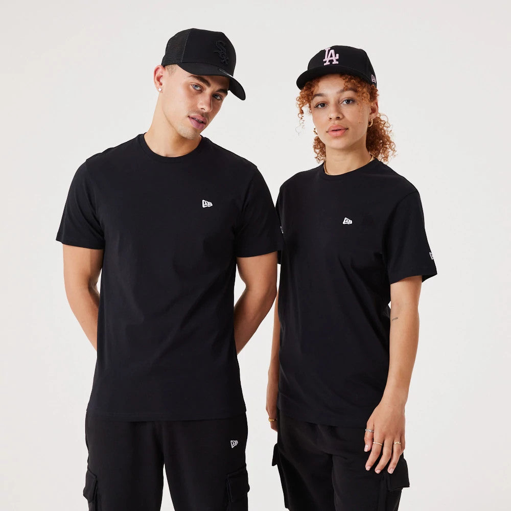 New Era Essential Black T-Shirt, on-model view showing two individuals wearing black t-shirts with a small debossed New Era logo on the front chest, paired with black caps featuring different raised logos on the front.