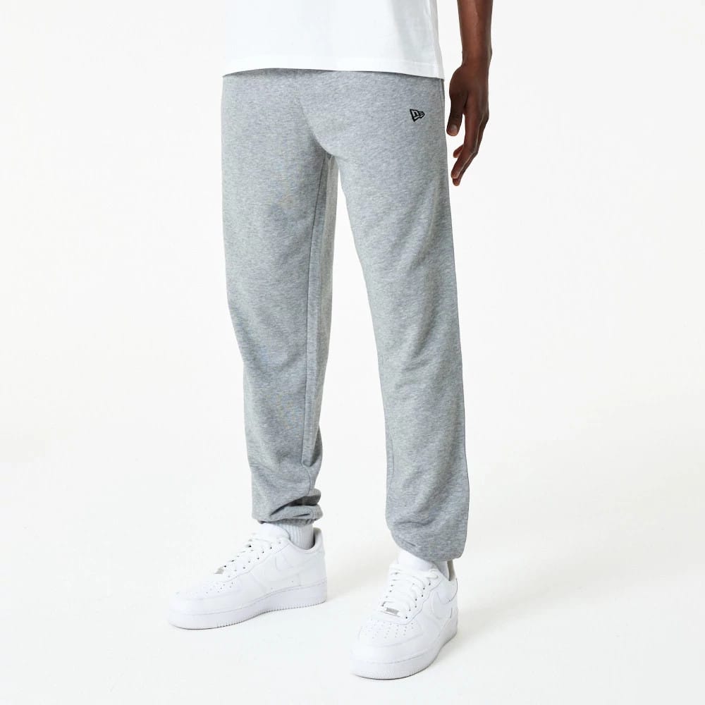 New Era Essential Grey Joggers, front view on a model with a relaxed fit, featuring the embroidered New Era flag logo on the upper left thigh, paired with white sneakers and a plain white T-shirt.