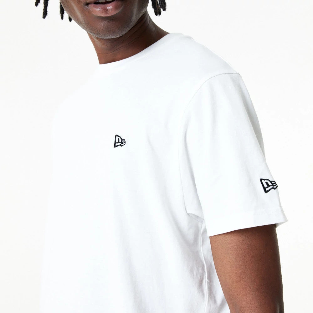 New Era Essential White T-Shirt, on-model view featuring a raised black New Era logo on the chest and another on the sleeve, highlighting the simple and classic design of the white t-shirt on the individual.
