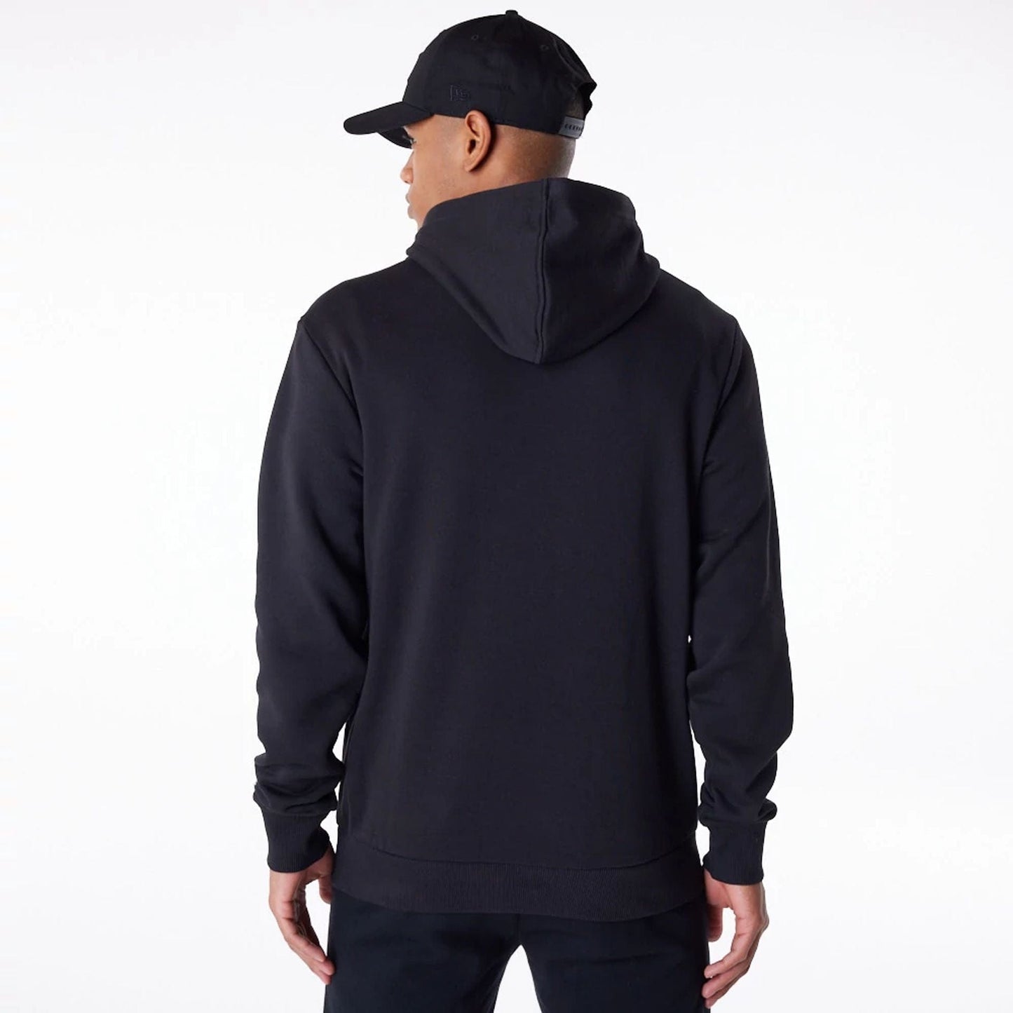 New York Yankees MLB Regular Black Pullover Hoodie, rear view showing the solid black fabric with a spacious hood and ribbed cuffs, worn by a person paired with a black cap featuring a raised New Era logo on the side.