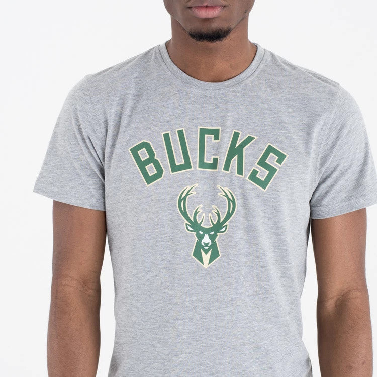 Milwaukee Bucks NBA Regular Grey T-Shirt, front view showing a heather grey short sleeve shirt with green "BUCKS" lettering arched across the chest above a stylised deer head logo, worn on-model.