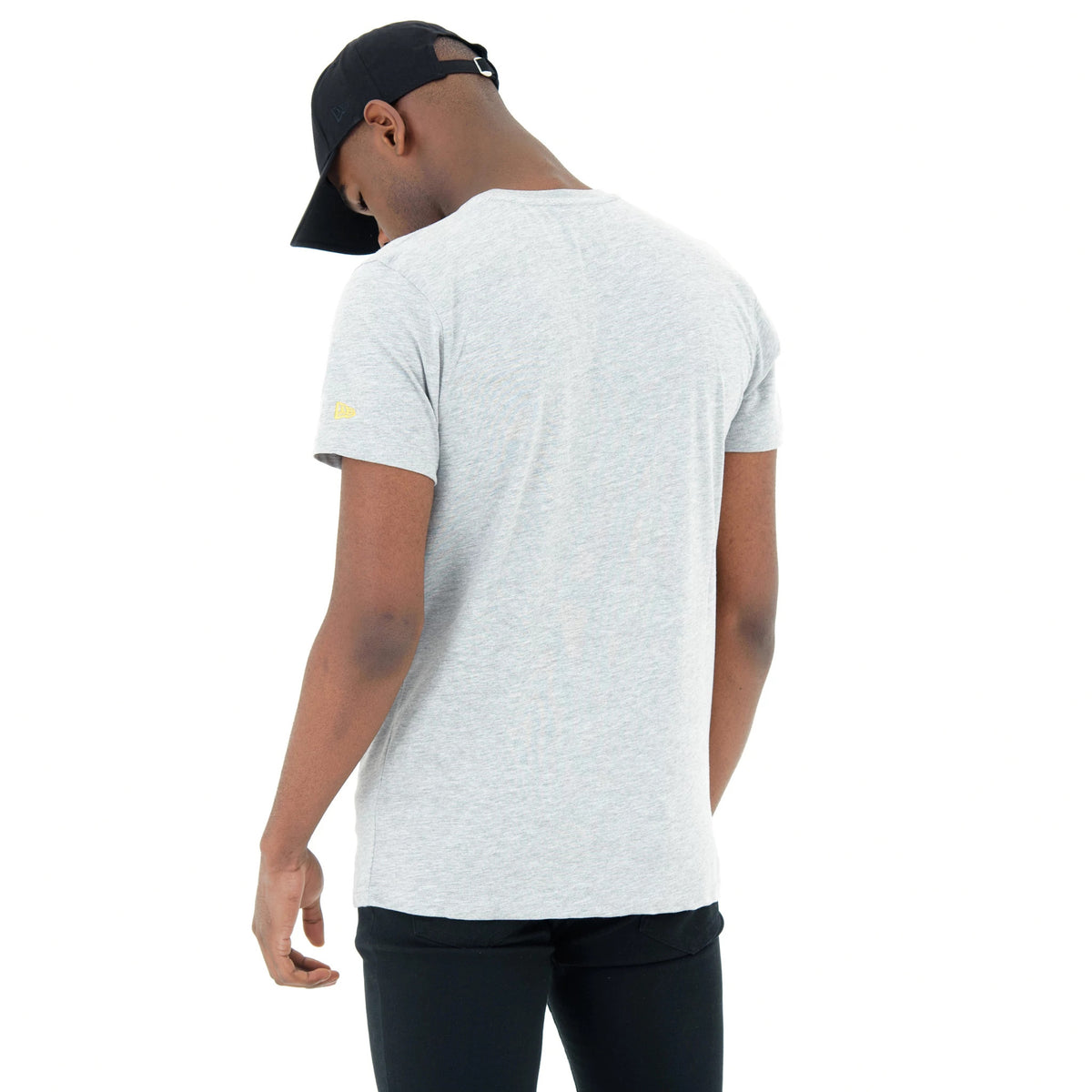 Golden State Warriors NBA Regular Grey T-Shirt, on-model rear view showing the plain grey back panel and the small yellow embroidered New Era logo on the sleeve, with a black cap worn by the model.