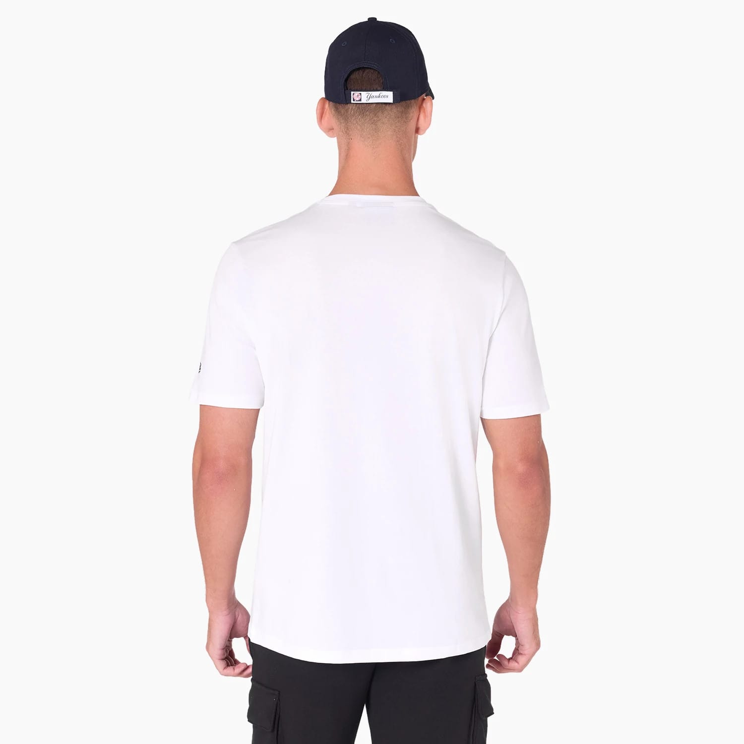 New York Yankees MLB White T-Shirt, rear view showing the plain white back panel, short sleeves with a small New Era logo on the left sleeve, worn by a model also wearing a navy cap.